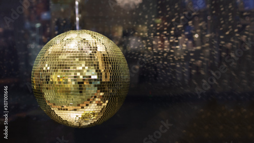 Golden mirror disco ball with bright golden rays, night party background with copy space.