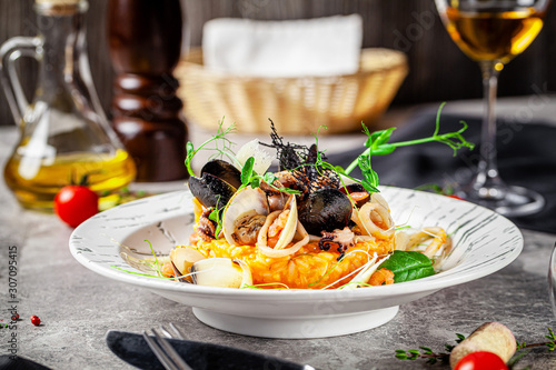 Italian food concept. Risotto with seafood, mussels, octopuses, squid. Serving dishes in a white plate. Modern serving in a restaurant. Background image. Copy space.