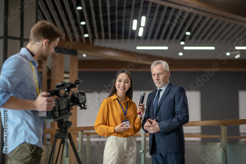 Reporters with videocamera having interview with famous businessman