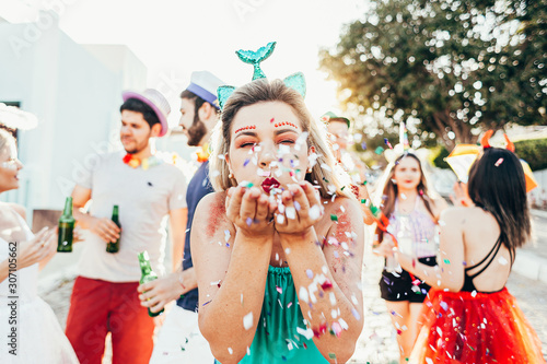 Brazilian Carnival. Young woman in costume enjoying the carnival party blowing confetti