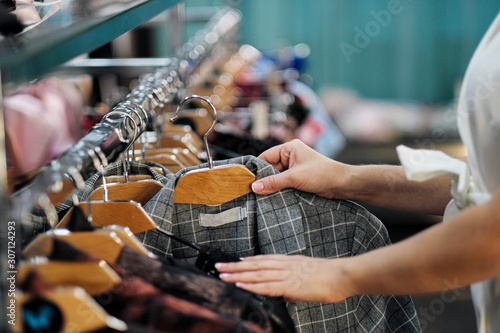 Close-up of the hands of a woman choosing clothes on a hanger in a store.