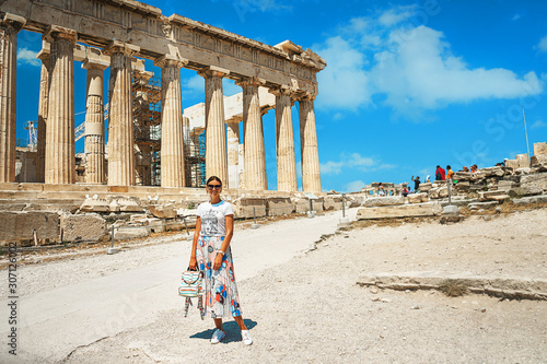 Ancient temple Parthenon in Acropolis Athens Greece and portrait of young woman on a bright blue sky background.