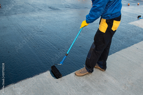 Worker applies bitumen mastic on the foundation