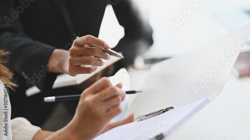 Closeup two woman consulting with paperwork document report.