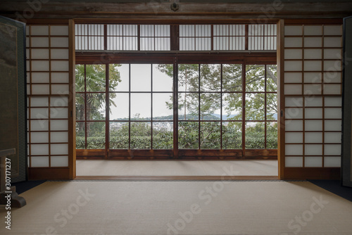 View of green trees and Kyoto from a window in a traditional room with shoji dividers and tatami in Honen-in temple