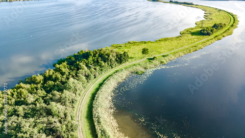 Aerial drone view of path on dam in polder water from above, landscape and nature of North Holland, Netherlands