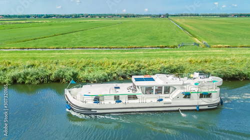 Aerial drone view of houseboat in canal and country landscape of Holland from above, family travel by barge boat and vacation in Netherlands