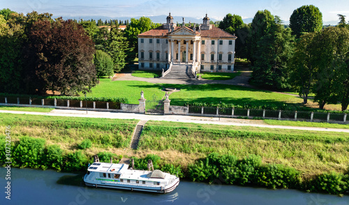 Aerial top view of ancient villa Giovanelli, garden and houseboat barge on canal Brenta from above, family vacation cruise on boat, Padua (Padova) in Veneto, Venice region, Northern Italy