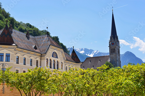 The spire of Vaduz Cathedral on the background of snowy alpine peaks