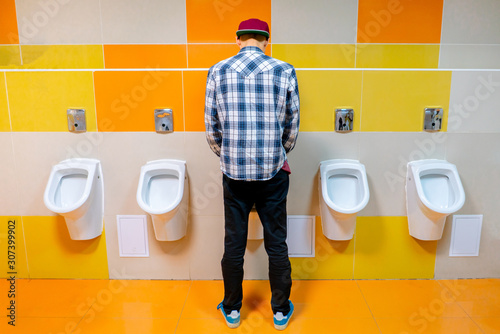 young man in the public toilet, standing next to the urinal in the trade center