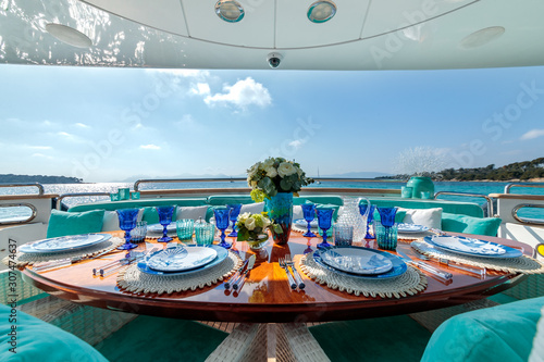 Ocean-themed table setting with blue plates, wine glasses and a flower bouquet on a luxury yacht