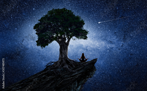 Yoga woman under a tree in front of the universe