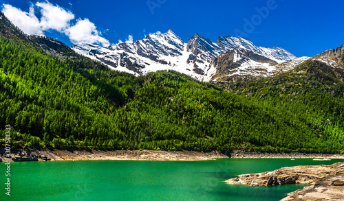 Green lake in Gran Paradiso Italian alps mountains in Graian Alps in Piedmont, Italy with snow capped peaks.