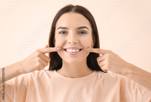 Beautiful young woman with healthy teeth on light background