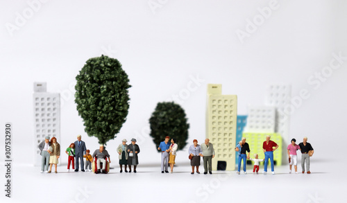 Any of various miniature families standing in front of miniature trees and miniature building.