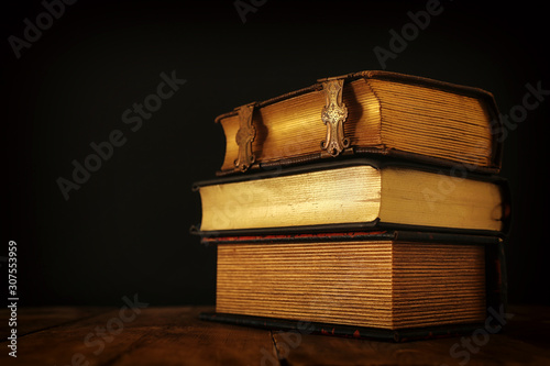 stack of antique books on old wooden table. fantasy medieval period and religious concept.