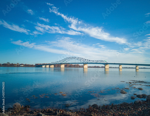 Historic blue and white arch truss bridge over the Columbia River with blue skies and clouds on a sunny morning in Kennewick-Pasco Washington