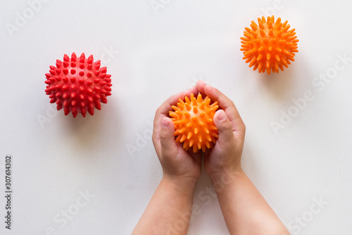 Spiky orange massage needle ball in child hands
