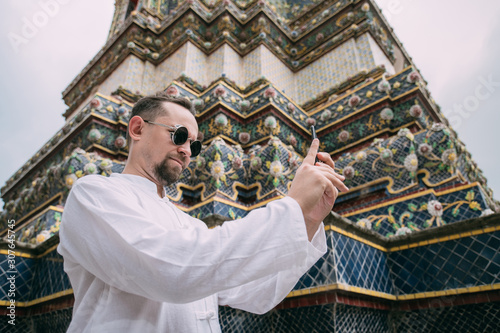A man in a Buddhist temple takes pictures, takes a selfie on the phone.