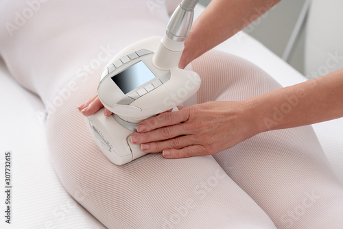 Woman in special white suit getting anti cellulite massage in spa salon. LPG and body contouring treatment