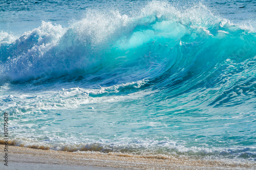 Turquoise colored breaking wave seascape on the beach