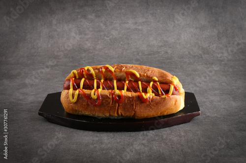 Sausage sandwich with mustard and ketchup on a dark gray background