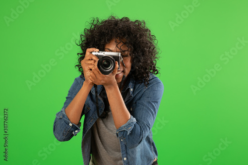 Portrait of happy black female photographer taking a photo on greenscreen