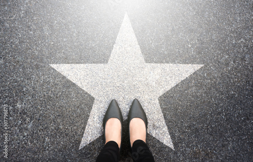 Success in business design concept. Businesswoman standing on street road background. Top view. Selfie of feet in black high heels shoes and white star symbol on pathway floor. New talent or champion.