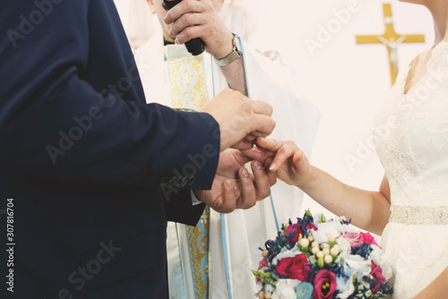 Nowożeńcy nakładają obrączki podczas wypowiadania słów przysięgi małżeńskiej.