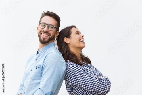 Joyful carefree couple leaning on each other, chatting and laughing at joke. Young woman in casual and man in glasses in glasses posing isolated over white background. Sweet couple concept