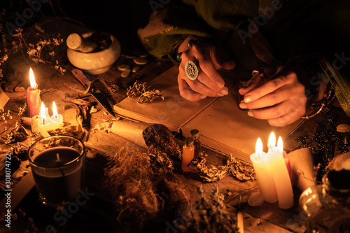 Hands fortune teller over an ancient table with herbs and books. Manifestation of occultism in the form of divination