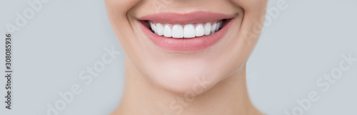 Perfect female smile on gray background. Healthy white teeth, advertising dentistry