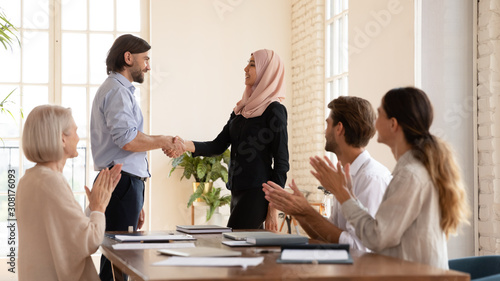 Smiling boss praising female islamic employee in hijab at office.
