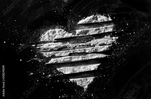 White powder in shape heart, cocaine line isolated on black background, top view, series