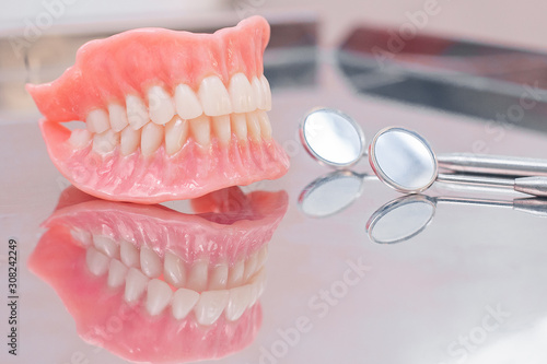 Two dentures. Instruments and dental hygienist checkup concept with teeth model dentures and mouth mirror. Regular dentist checkups