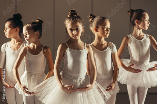 group of caucasian cute girls 7-8 years old dancing classic ballet together wearing white tutu skirts and pointe shoes