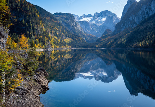 Peaceful autumn Alps mountain lake. Gosauseen or Vorderer Gosausee lake, Upper Austria. Dachstein summit and glacier in far.
