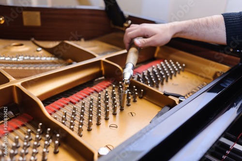 Man tuning traditional upright piano for jazz. hand of a man tuning piano, close up