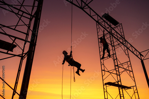 Male working abseiling on a construction site silhouette worker