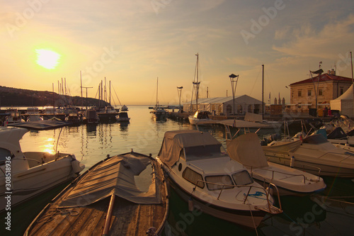 Amazing autumn landscape of harbor during sunset. Sailboats and yachts moored in marina of Koper and reflected in quite water. Famous touristic place and romantic travel destination in Slovenia