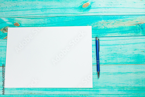 Niebieski długopis i kartka na turkusowym tle