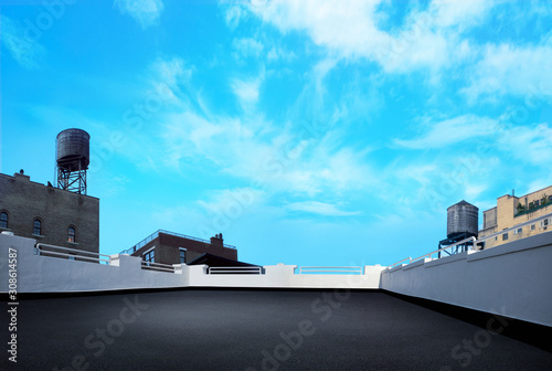 city building rooftop deck with watertowers and blue nice day sky and clouds