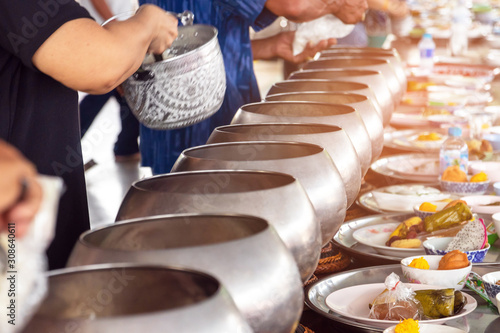 Buddhist alms giving ceremony in the morning. Offerings in a Monk's alms bowl. The tradition of giving alms to monks in Thailand. 