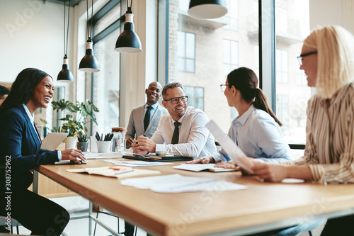 Diverse businesspeople laughing during a meeting around an offic