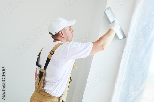 Painter with putty knife. Plasterer smoothing esconson surface at home renewal