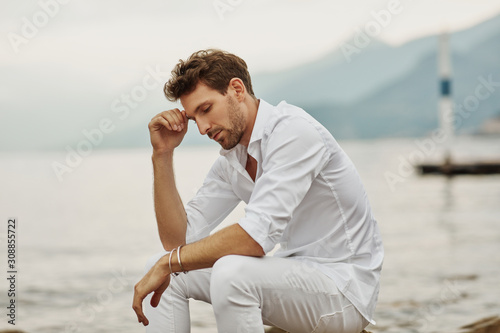 Handsome male model thinking outdoor on a background of lake and mountains