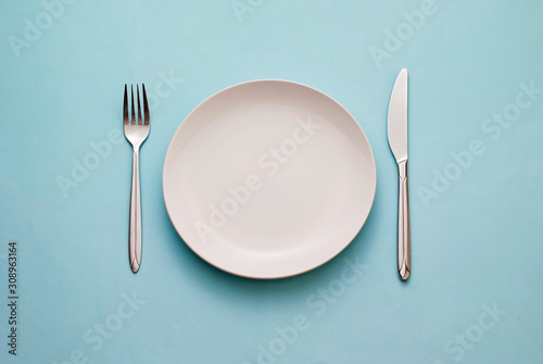 Clean empty white plate with knife and fork