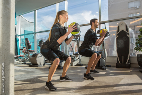 Man and woman doing electro muscular stimulation training in a modern gym