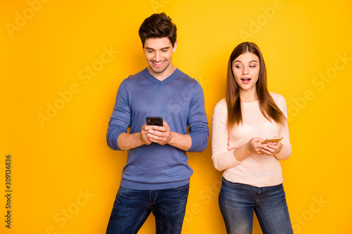 Suspicious woman want know what her husband post in his blog use cell phone look smartphone screen wear pink blue pullover denim jeans isolated over shine color background