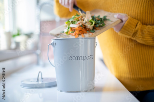 Close Up Of Woman Making Compost From Vegetable Leftovers In Kitchen